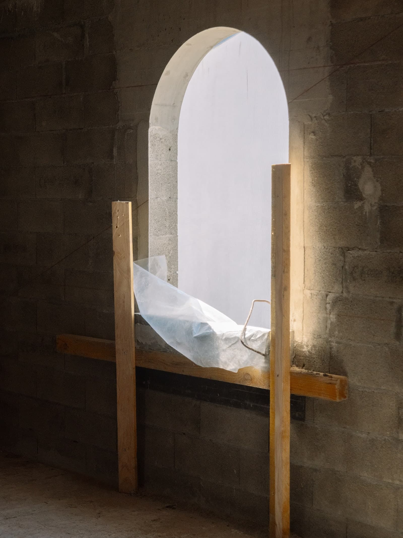 Fenêtre en arche en cours de création sur le chantier, étai de bois et lumière rasante sur la maçonnerie brute.